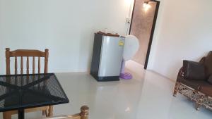 a room with a refrigerator and a table and a chair at Raina-Suanpa Lung Sood Farmstay in Ban Mot Deng