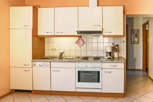 cocina con armarios blancos y fogones en Sonnenschein - a52658, en Klausdorf