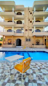 a swimming pool with a table and chairs in front of a building at DREAM ISLAND Hotel in Luxor