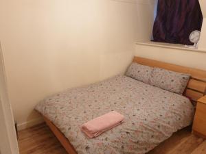 a small bedroom with a bed with a pink towel on it at Splendid 4Bedrooms Shared Home in Manchester