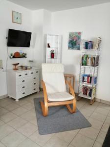 a living room with a white chair and a tv at 76 qm Whg im EG Haus-Wohlfühloase vor der Haustür in Gladenbach