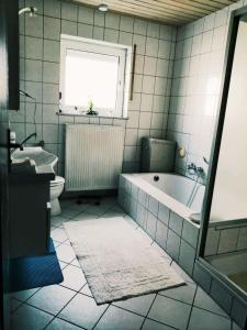 a bathroom with a tub and a toilet and a sink at 76 qm Whg im EG Haus-Wohlfühloase vor der Haustür in Gladenbach