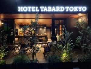 dos personas sentadas en sillas fuera de un hotel tarbad tofu en HOTEL TABARD TOKYO en Tokio