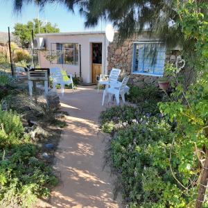 un patio con sedie bianche e una casa di Neels Cottage a Clanwilliam