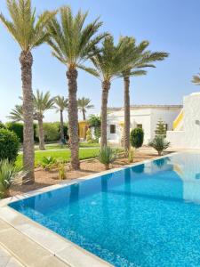 a pool with palm trees in front of a house at Dar El Jerbi in Mezraya