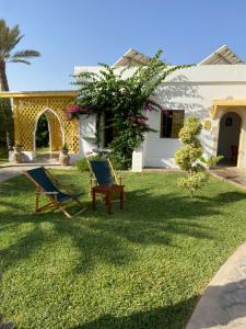 a yard with two chairs and a house at Dar El Jerbi in Mezraya