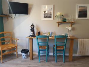 a table with two chairs and a table with a television at LES LUPINS in Étretat
