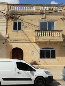 une camionnette blanche garée devant un bâtiment dans l'établissement Dynesty B&B, à Birżebbuġa