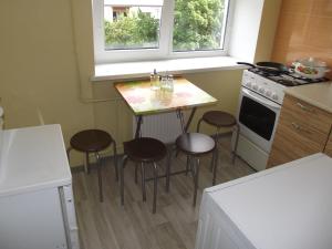 uma pequena cozinha com uma mesa e bancos em Brīvības 21 Apartament em Ventspils