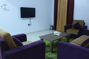 una sala de espera con sillas, mesa y TV en Al Karam Hotel Apartment en Nizwa
