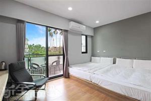 1 dormitorio con 1 cama, 1 silla y balcón en Ark stay方舟文旅山嵐新館溜滑梯商務民宿, en Jiji
