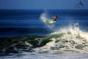 un hombre montando una ola en una tabla de surf en el océano en Hotel Los Mangos El Salvador, en El Cuco