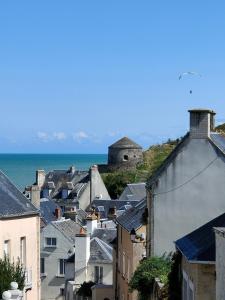 a city with houses and the ocean in the background at Fishermen's Friend in Port-en-Bessin-Huppain