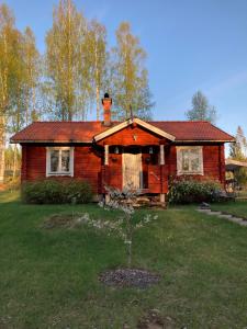 une maison en bois avec un arbre en face de celle-ci dans l'établissement Trevlig stuga med endast 300 m till Dalälven., à Rudö