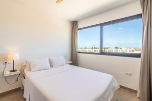 a bedroom with a white bed and a large window at Flatguest CotilloMar Volcano in Cotillo