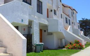 un edificio blanco con escaleras y flores en el césped en Apart Hotel Sendero del Sol, en La Serena
