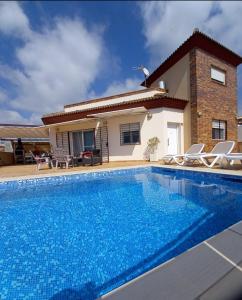 a villa with a swimming pool in front of a house at Villa Las Tres J in Málaga