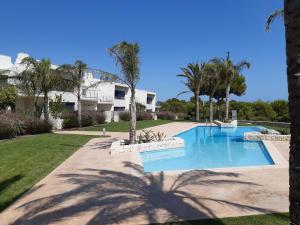 einen Pool in einem Garten mit Palmen in der Unterkunft Prachtig penthouse appartement op Lo Romero golf in Pilar de la Horadada