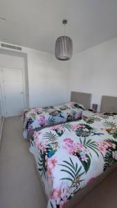 um quarto com duas camas com flores em Prachtig penthouse appartement op Lo Romero golf em Pilar de la Horadada