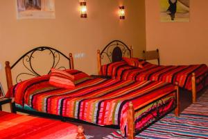 two beds in a bedroom with red and orange striped sheets at LESCALE DE OUARZAZATE in Ouarzazate