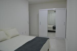 um quarto branco com uma cama e um espelho em Apartamento Praia do Santinho em Florianópolis