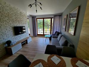 a living room with a couch and a tv at Apartament Jurata Deluxe in Jurata