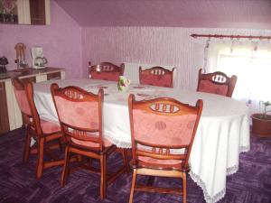 tavolo da pranzo con 4 sedie e una tovaglia bianca di Pensiunea Floare de Bucovina a Frasin
