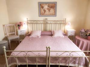 a bedroom with a bed with pink sheets and two chairs at B&b il Giardino da Pina in Tuili