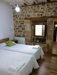 a bedroom with two beds and a stone wall at Cabaña Pasiega Única in Selaya