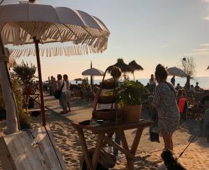 un groupe de personnes debout sur une plage avec un parasol dans l'établissement Klein Langeveld, à Noordwijkerhout