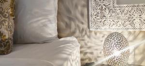 a bed with white sheets and pillows and a table at Riad Kech Soul Boutique & Spa in Marrakesh
