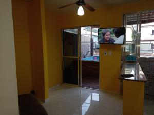 sala de estar con paredes amarillas y TV de pantalla plana. en Cantinho Feliz de Muriqui / Casa amarela, en Mangaratiba