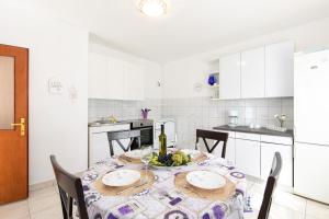 a white kitchen with a table with a bottle of wine at Apartment "GOTA" , 60m2 , za 2 osobe in Risika