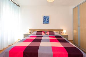 a bedroom with a bed with a red white and black blanket at Apartment "GOTA" , 60m2 , za 2 osobe in Risika