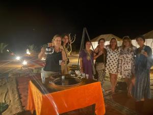 a group of women standing around a table on the beach at Sahara Happy Camp in Merzouga