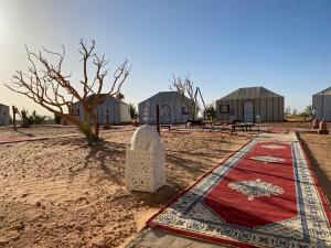 a view of a mosque with a red rug in front of buildings at Sahara Happy Camp in Merzouga