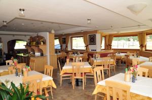 um restaurante com mesas e cadeiras brancas e janelas em Hotel Ciamol em Mazzin