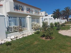 una casa blanca con una valla y algunas plantas en DolfinHouse en Yzerfontein