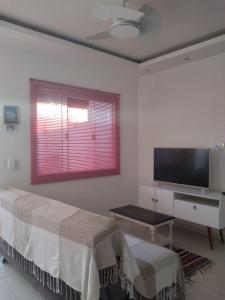 a living room with a bed and a flat screen tv at Casa com Jardim na Praia de Guaratiba, Maricá in Maricá