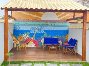 a patio with chairs and a mural on a wall at Casa com Jardim na Praia de Guaratiba, Maricá in Maricá