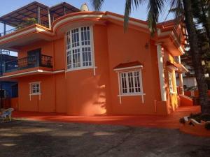 a orange house with a palm tree in front of it at Stunning luxury Villa in Goa India in Colva