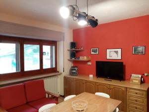 un soggiorno con pareti rosse, tavolo e TV di Casa Vacanza Giardino a Guardiabruna