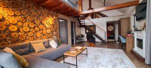 a living room with a couch and a wall of logs at CABANA CEITREI - MOUNTAIN VIEW GIUMALAU in Cozăneşti