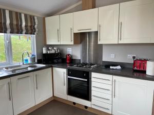 een keuken met witte kasten en een fornuis met oven bij The Southwick lodge in Morpeth