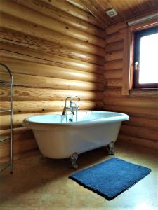 ein Badezimmer mit einer Badewanne an einer Holzwand in der Unterkunft Osiers Country Lodges in Diss
