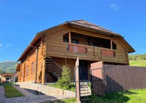 una casa in legno con una recinzione di fronte ad essa di Chalet Borzhava a Huklyvyy
