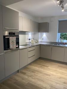 a kitchen with white cabinets and a wooden floor at Water Walk Apartment in Edinburgh