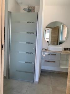 La salle de bains est pourvue d'une porte, d'un lavabo et d'un miroir. dans l'établissement Les Chambres de Lily 2, à Lorgies
