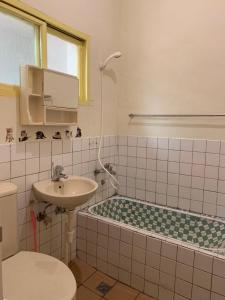 La salle de bains est pourvue d'un lavabo, d'une baignoire et de toilettes. dans l'établissement Guan Ma Homestay, à Miaoli