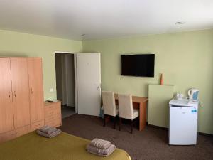um quarto de hotel com uma mesa e uma televisão na parede em Laisves 30 em Mažeikiai